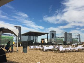 A outdoor event with chairs pointed towards a projector screen