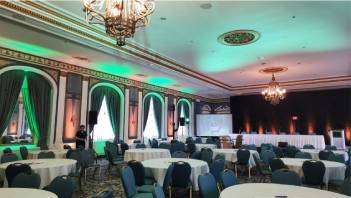 A large hall setup for a gathering with multi-coloured lights illuminating the walls