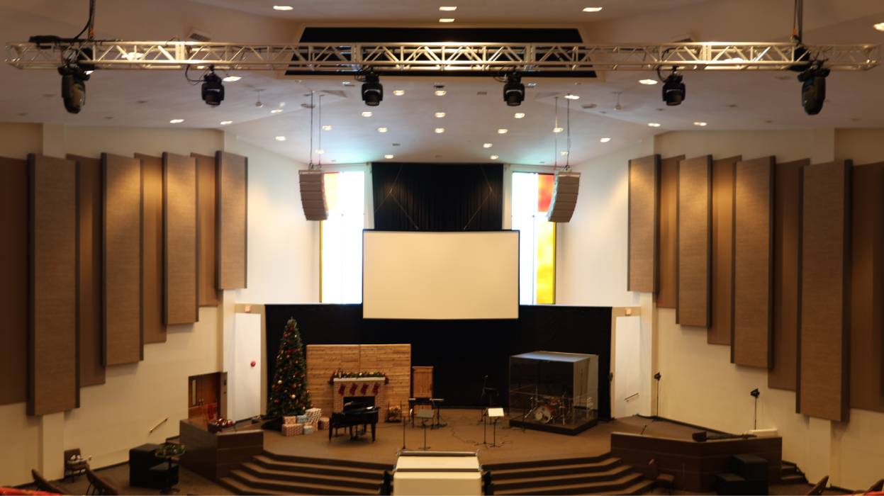 A church stage with a suspended projecton screen.